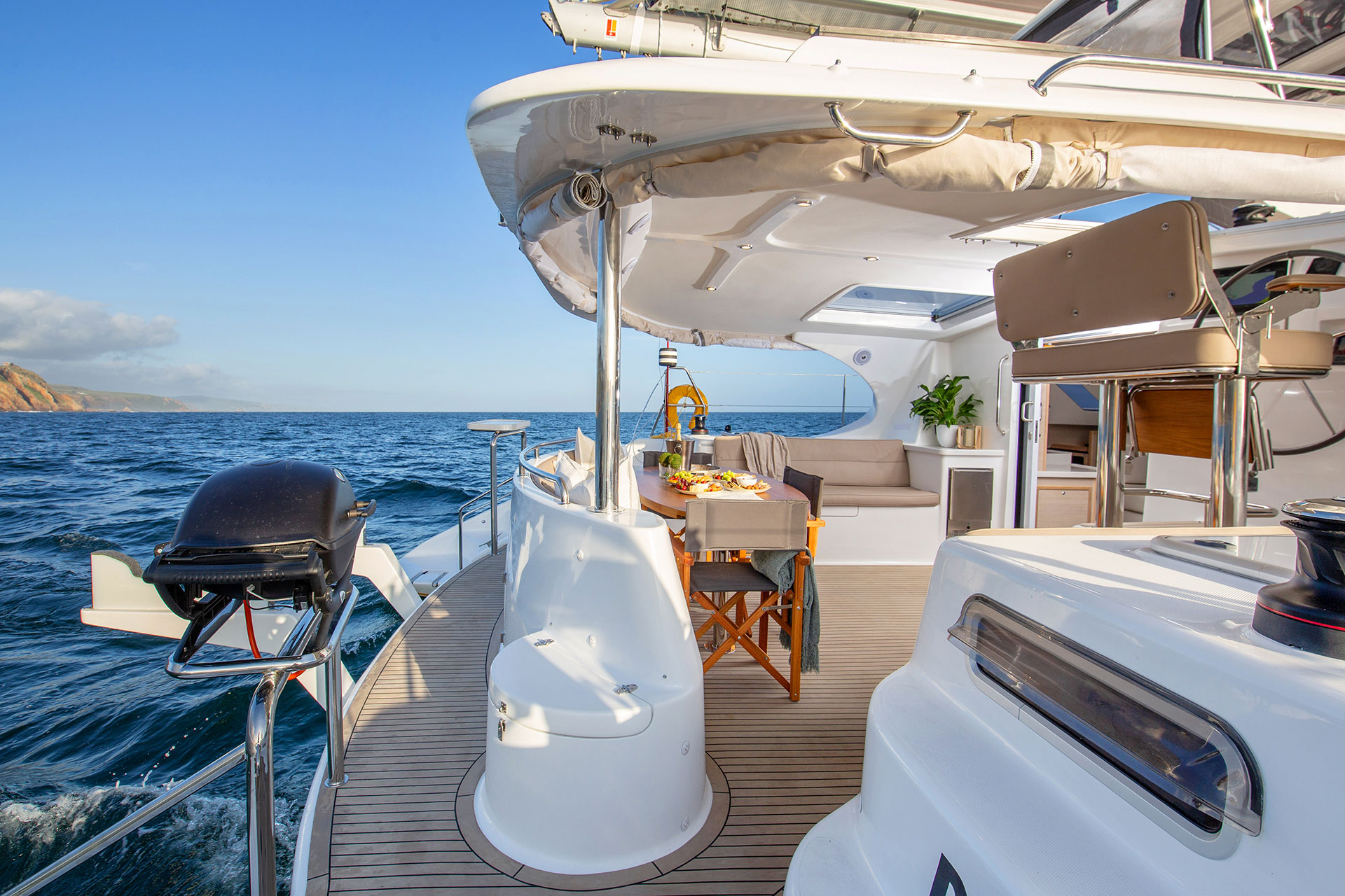 Luxury catamaran aft cockpit with dining area and ocean backdrop, illustrating the quality and craft behind KYC catamarans.